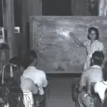Ana F. Duenas teaching children in bomb-shattered building on January 1945. Micronesian Area Research Center (MARC) collection.