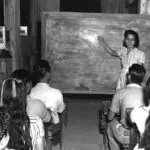Carousel Image: Ana F. Duenas teaching children in bomb-shattered building on January 1945. Micronesian Area Research Center (MARC) collection.