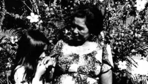 A child nginge's her elder while uttering 'ñora and receives a blessing, "dioste ayudi" in response. Rene Mahone/Micronesian Area Research Center (MARC)