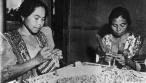 Maria Limtiaco (right) along with her sister, Rita Perez Torres, makes snail shell purses shortly after World War II in Sinajana to sell to visitors to Guam. Photo courtesy of Pale Eric Forbes, OFM, Cap.