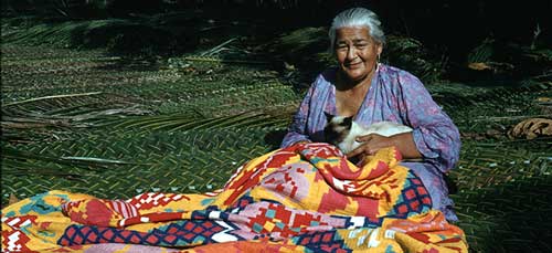 Woman sewing a tivaevae, quit. Photo take on Rarotonga, Cook Islands. Photo from the Alexander Turnbull Library Archive provided by Wikimedia Commons.