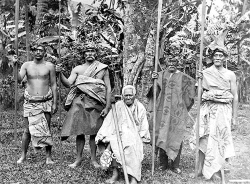 Makea Karika Ariki (sitting) and nobles of the Makea Karika tribe, Rarotonga, Cook Islands. From the Alexander Turnbull Library provided by Wikimedia Commons.